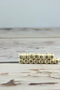 Close-up of text on table at beach against sky