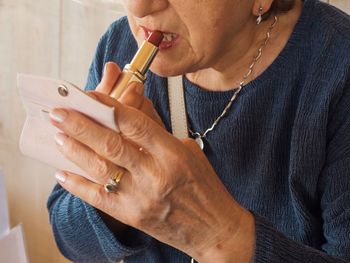 Midsection of woman applying lipstick