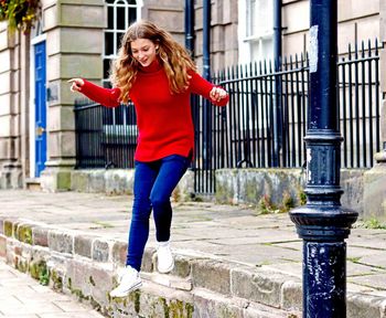 Young woman jumping from steps against fence