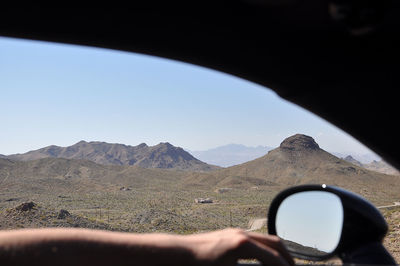 Midsection of person in car against mountain range