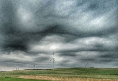 Low angle view of wind turbines on field