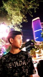 Portrait of young man looking at illuminated city at night