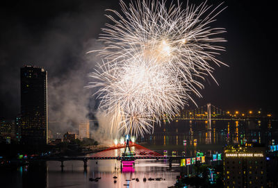 Firework display over river in city at night