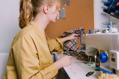 Side view of tailor using sewing machine