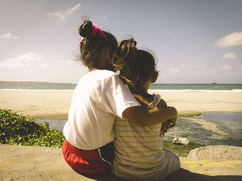 Girls appreciating the ocean and not the sewer that lies between them