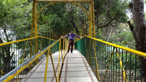 Rear view of man walking on footbridge