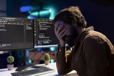 Side view of man using laptop at office