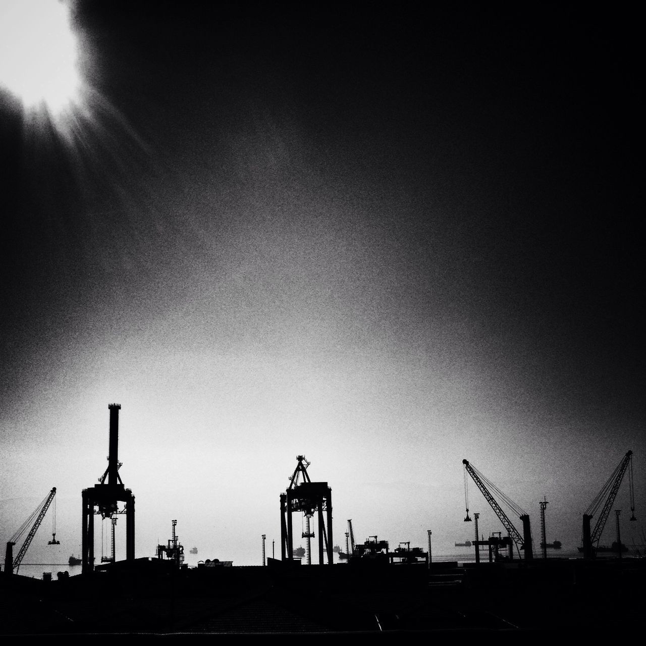 low angle view, silhouette, sky, copy space, clear sky, built structure, industry, street light, sunset, outdoors, architecture, sunlight, crane - construction machinery, construction site, dusk, technology, no people, sun, nature, lighting equipment