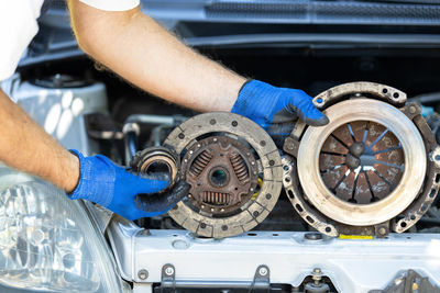 Automotive worker holding used car clutch disc, pressure plate and release bearing