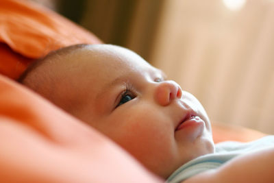 Close-up of cute baby girl lying on bed