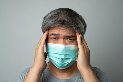 Portrait of teenage girl covering face against gray background