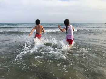 Rear view of men on beach against sky