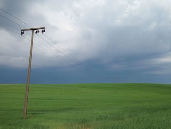 Windmill on field against cloudy sky