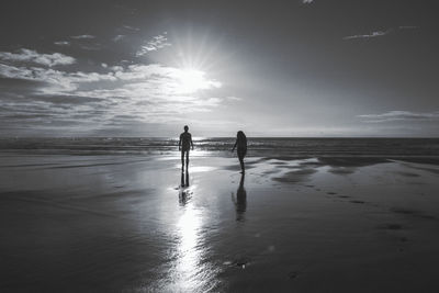 Silhouette people standing on beach against sky