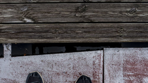 Low section of man standing on wooden plank