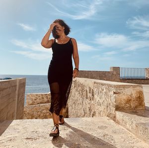 Full length of young woman standing against wall - ibiza