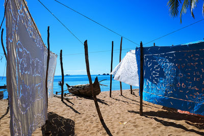 Clothes drying on beach against clear blue sky