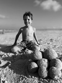 Portrait of young woman sitting on rock at beach