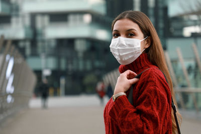 Portrait of young woman in mask standing outdoors