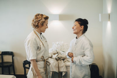 Cheerful female restaurant owners talking while standing against wall