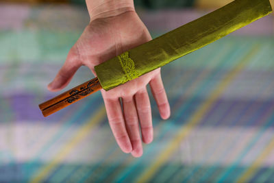 Cropped hand holding chopsticks in container