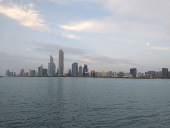 Sea and buildings in city against sky