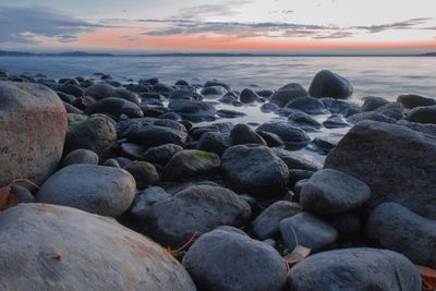 Rocks on beach against sky during sunset