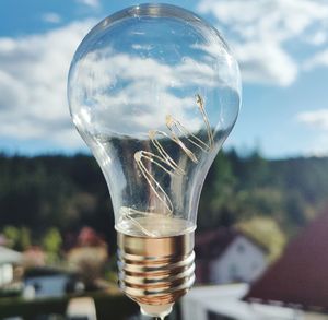 Close-up of glass of light bulb against sky