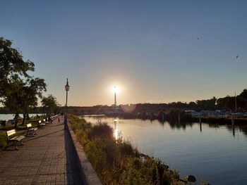 Street by river against sky at sunset