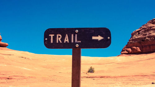 Road sign on desert against clear blue sky