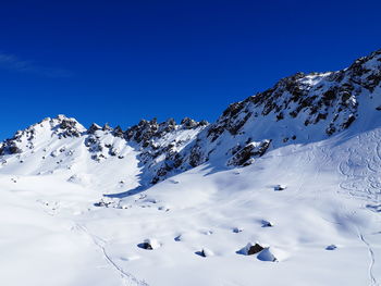 Low angle view of snow covered mountain against blue sky