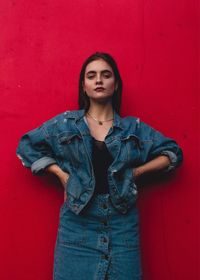 Portrait of beautiful young woman standing against red wall