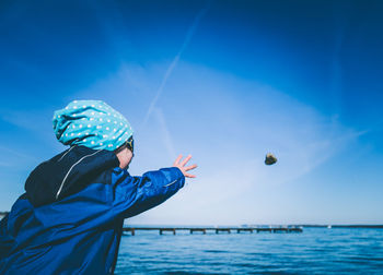 Man playing in sea against blue sky