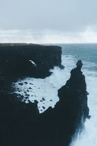 Rock formation in sea against sky