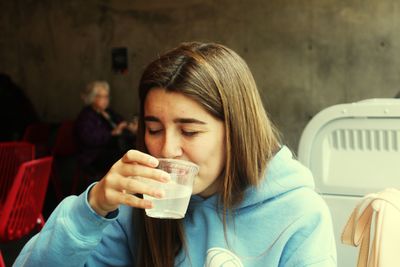 Teenage girl drinking drink at sidewalk cafe