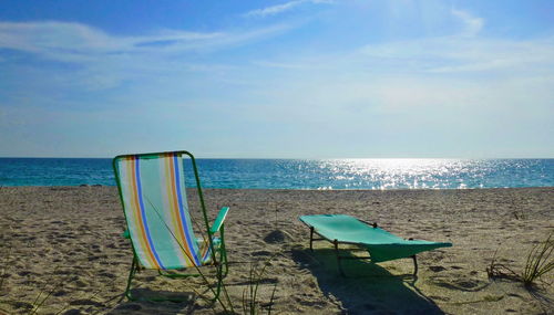 Chairs on beach against sky