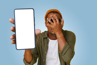 Midsection of woman using mobile phone against blue background