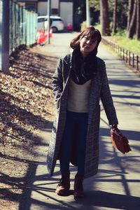 Young woman standing on footpath in city