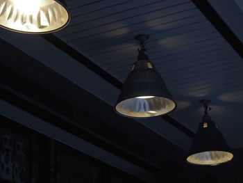 Low angle view of illuminated light bulb hanging from ceiling