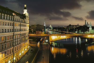 Illuminated bridge over river in city at night