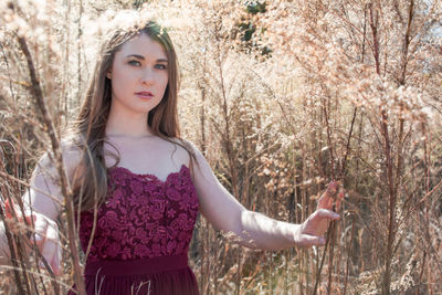 Portrait of young woman standing against plants