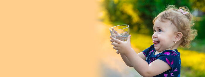 Portrait of woman holding drink against yellow background