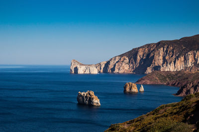 Scenic view of rocks in sea against blue sky