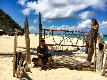 Man sitting on beach against sky