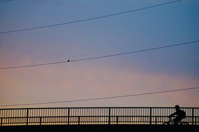 Silhouette man on bridge against sky during sunset