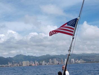 Flag by sea against sky in city