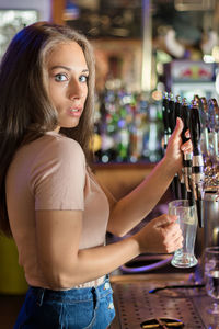 Close-up of a smiling young woman with drink in restaurant