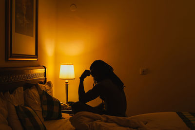 Side view of woman sitting on bed