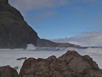 Rock formation on beach against sky