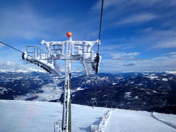 Ski lift over snowcapped mountains against sky